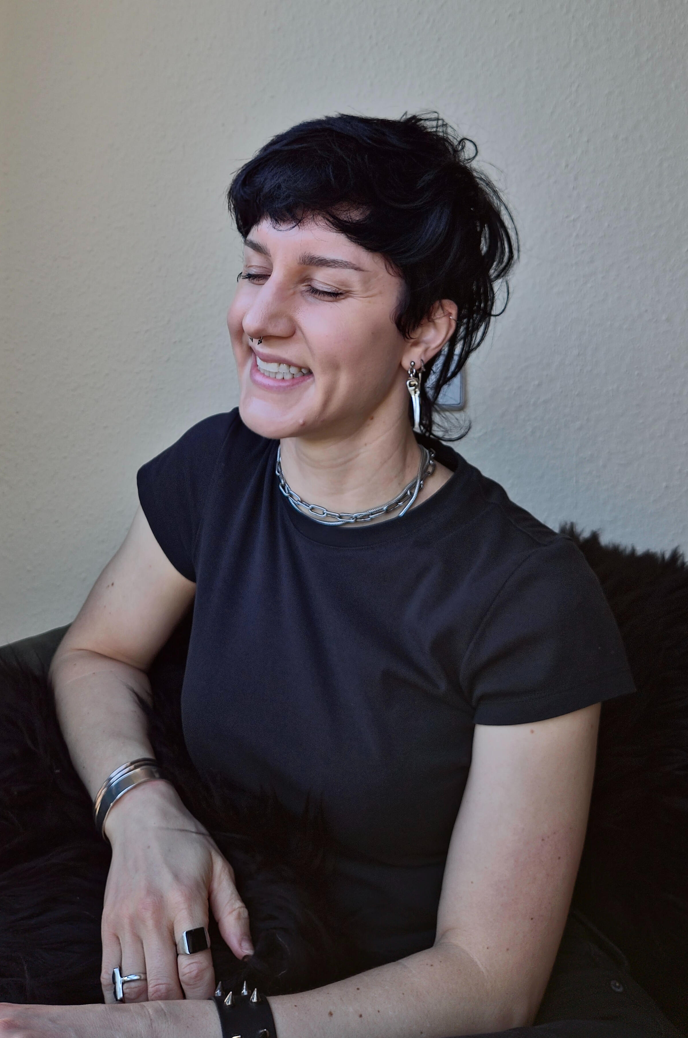 Molly Daszuta, laughing on their comfy couch, in Jena, Germany.